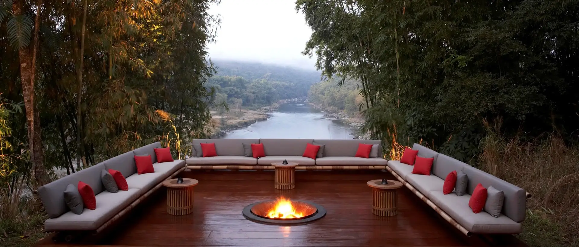 An open fire pit with seating on three sides and views over the river.