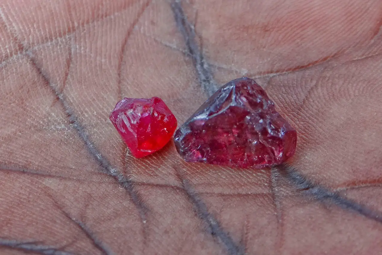 Two rubies being held in the palm of a hand