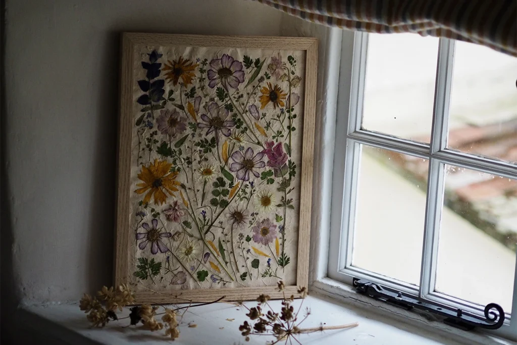 Pressed wildflowers in a frame by a window