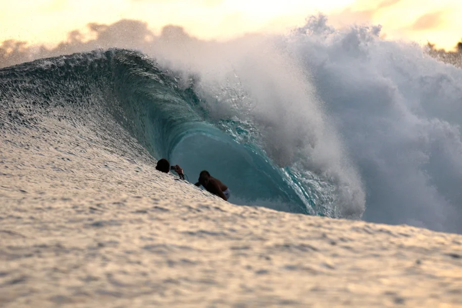 A surfer and a photographer on a Tropicsurf trip inside a wave tunnel about to crash down