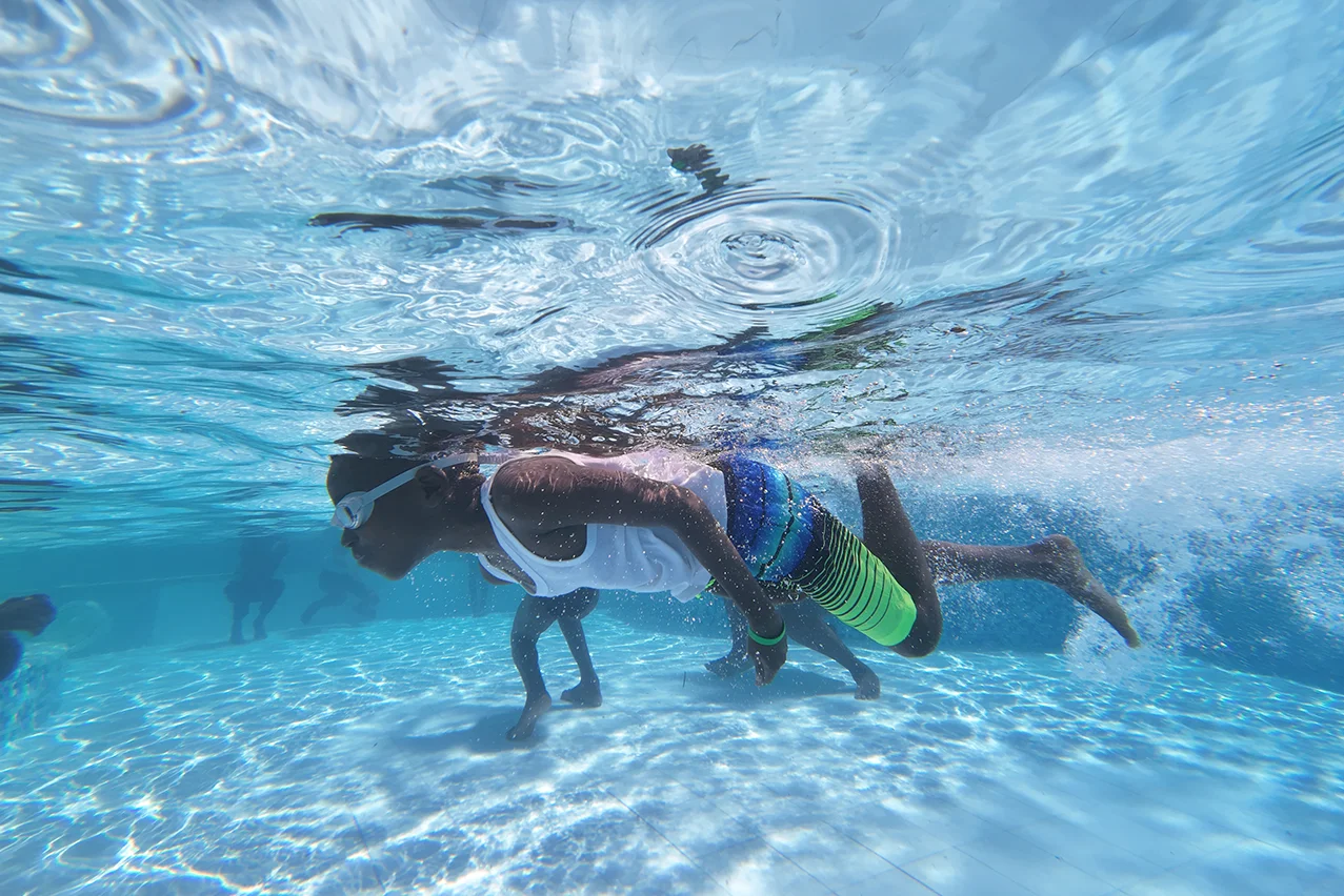 Young boy swimming in shallow turquoise waters as part of the Seas4Life Foundation work